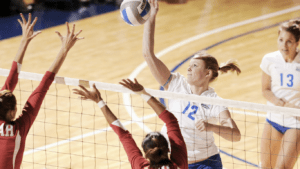 a group of people playing volleyball in a gymnasium