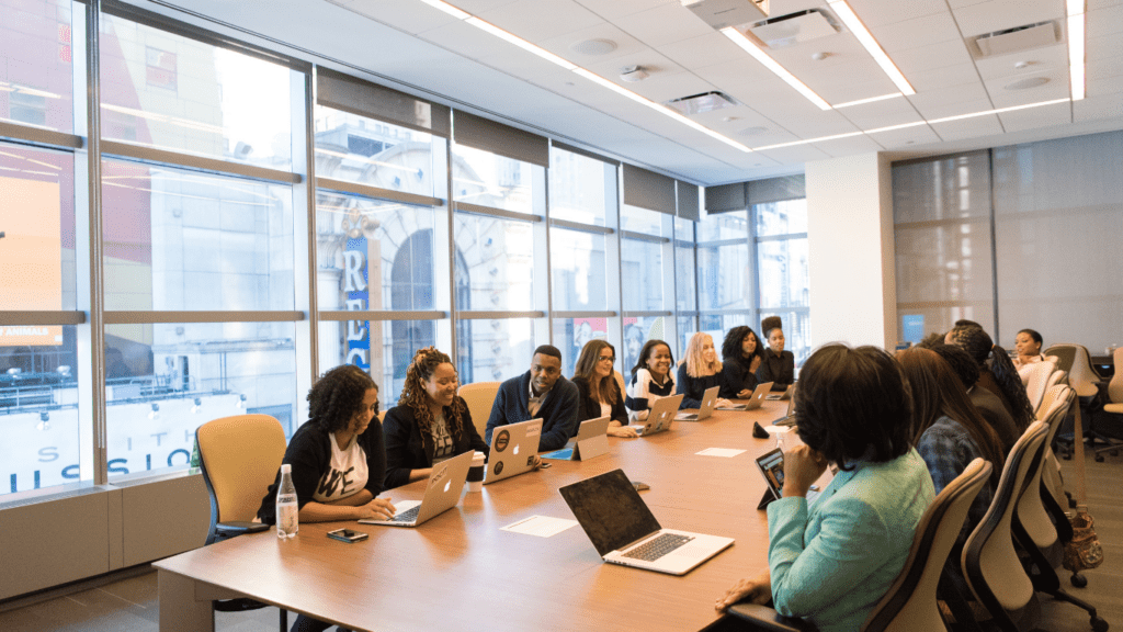 a group of people sitting around a conference table with laptops