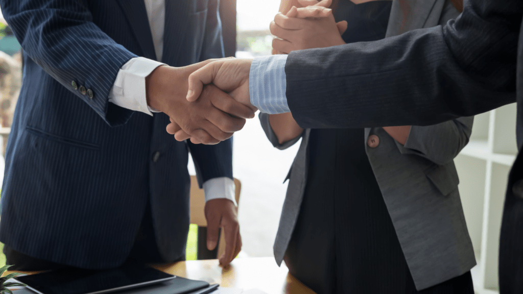 Two business people shaking hands over a piece of paper