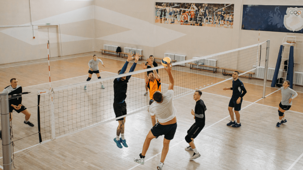 a group of people playing volleyball in a gymnasium