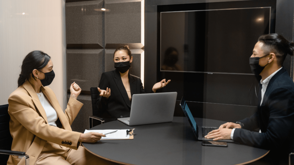 a group of people sitting around a conference table with laptops