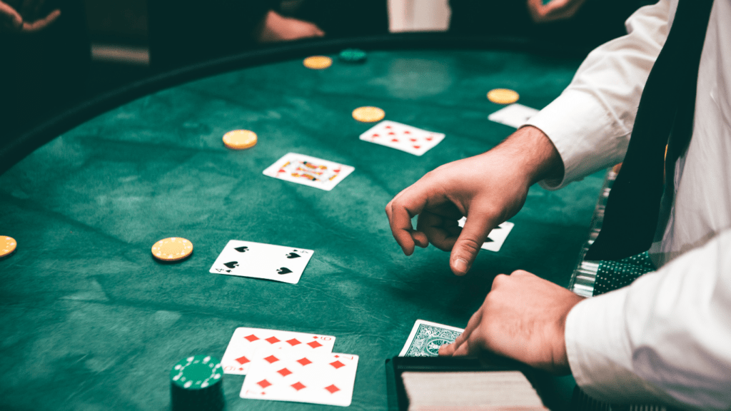 a person holding a pair of playing cards on a green table